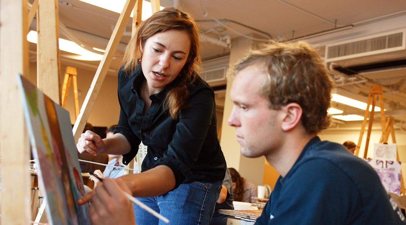 an art professor helps a student with a painting